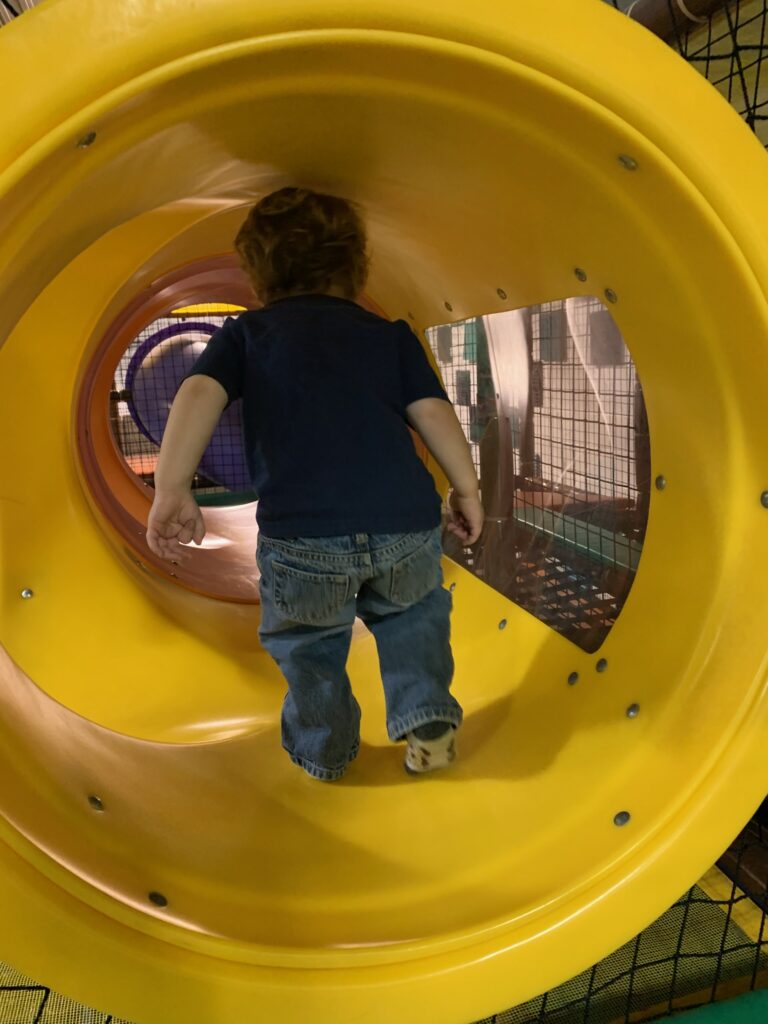 Toddler in a play tunnel at Recharge & Play Wellness Cafe in Waterloo, Ontario